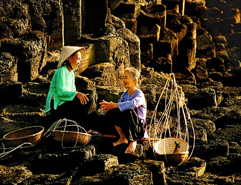 Fishermen resting, chatting inside the spectacular coastal rocks creating poetic space, unique fishing village in the central region.