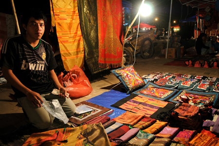 A vendor displays his woven textiles for sale at the night market, Vientiane