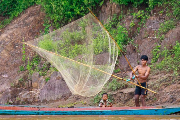 Fisherman and his child on boat are casting fishing net, Tad Ngeuan