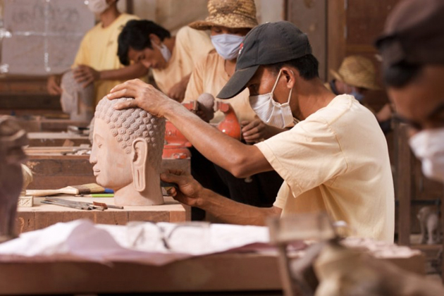 Artisans carving the Buddha statue at Artisans d'Angkor