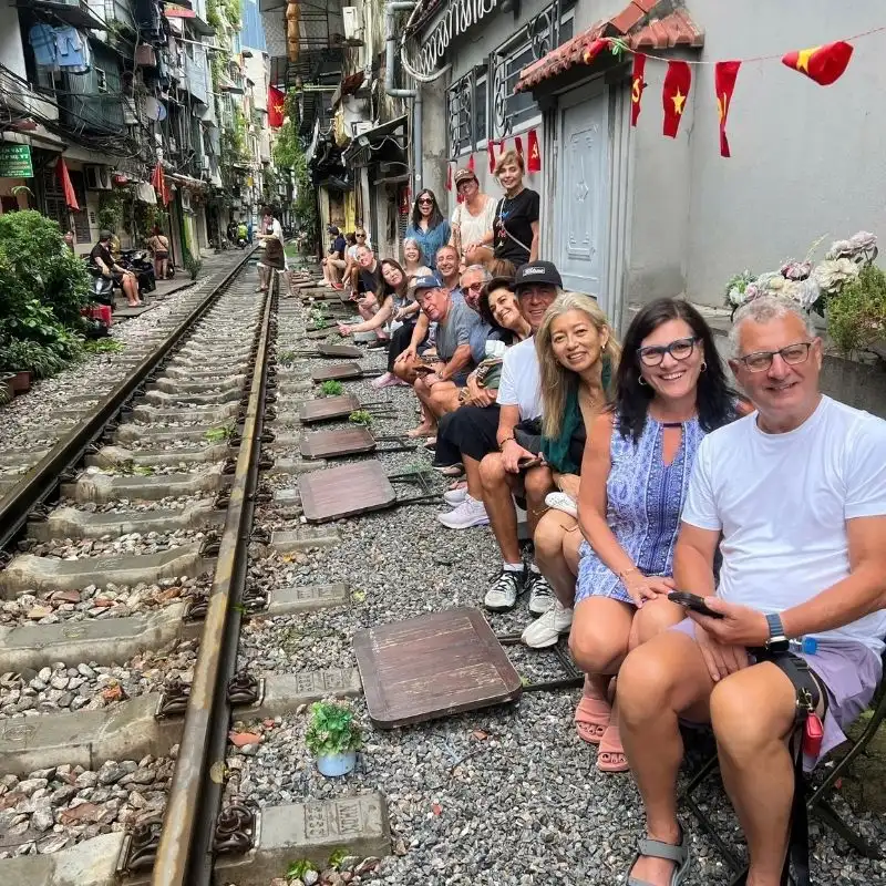 Small group travelers exploring iconic railway street in Hanoi with VietVisionTravel